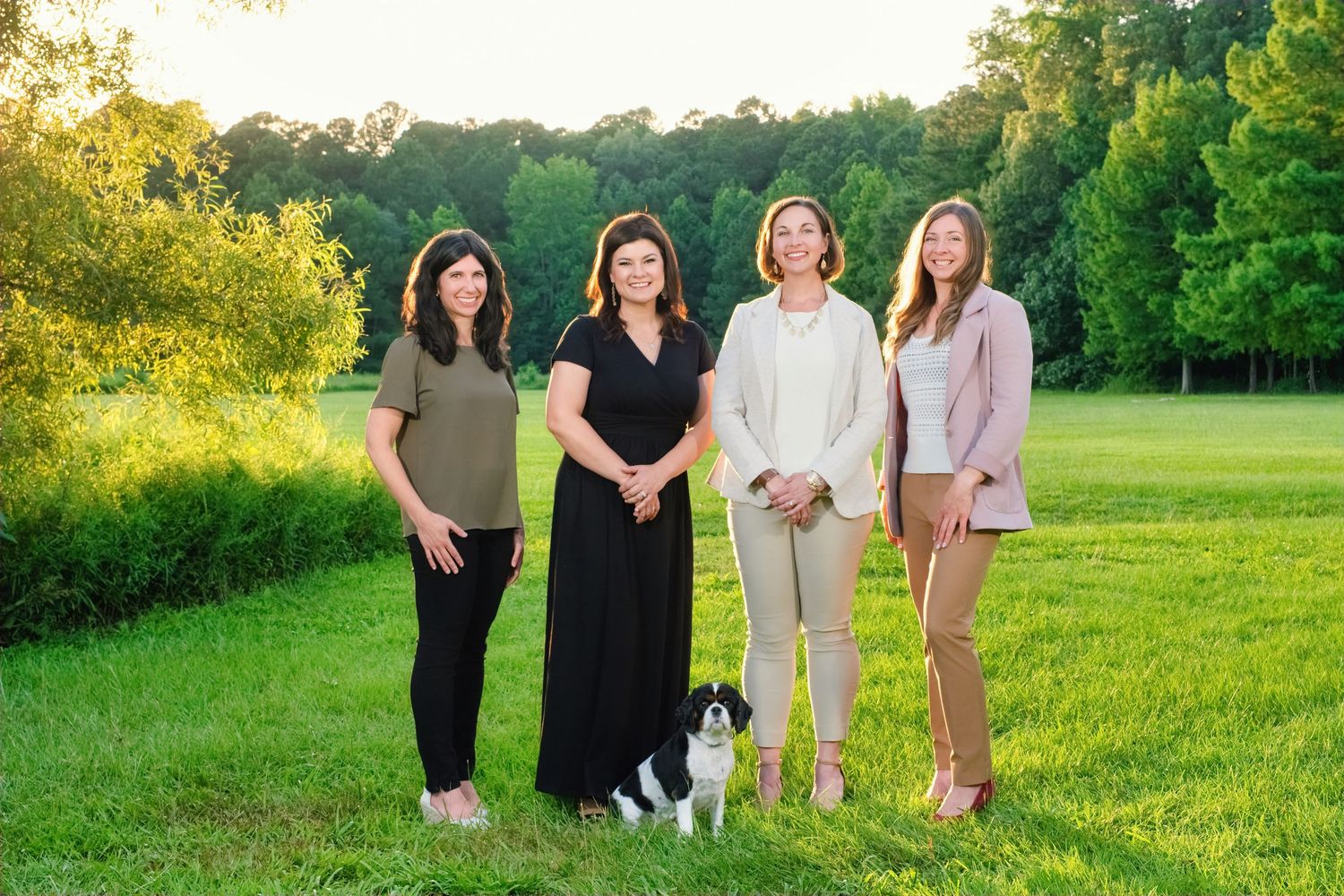 Professional outdoor family photo session in green field at golden hour with photographer capturing multiple poses.