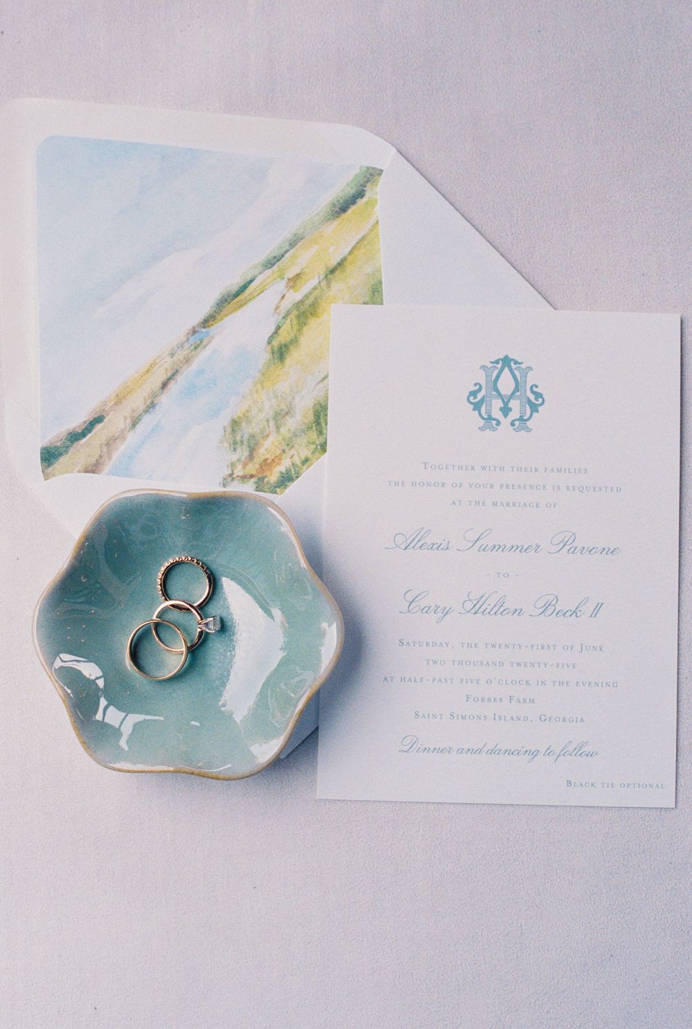 Elegant wedding stationery set with watercolor designs and delicate turquoise ceramic ring dishes on light gray background. saint simons