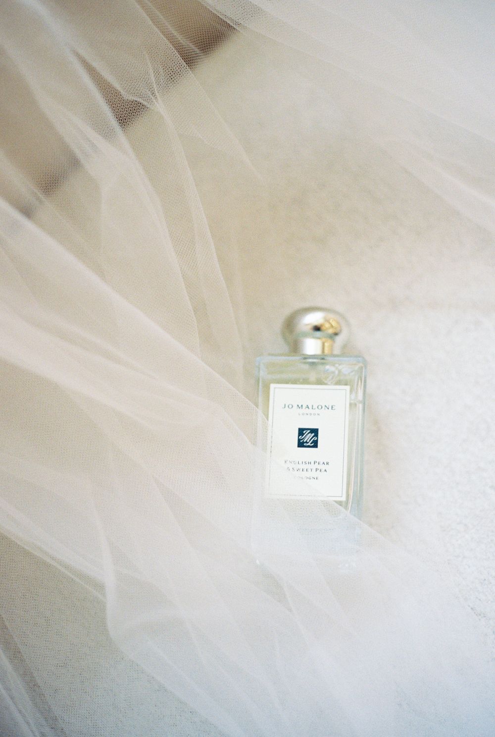 Delicate white tulle fabric creates an ethereal layered texture with a small perfume bottle and jewelry box visible.
