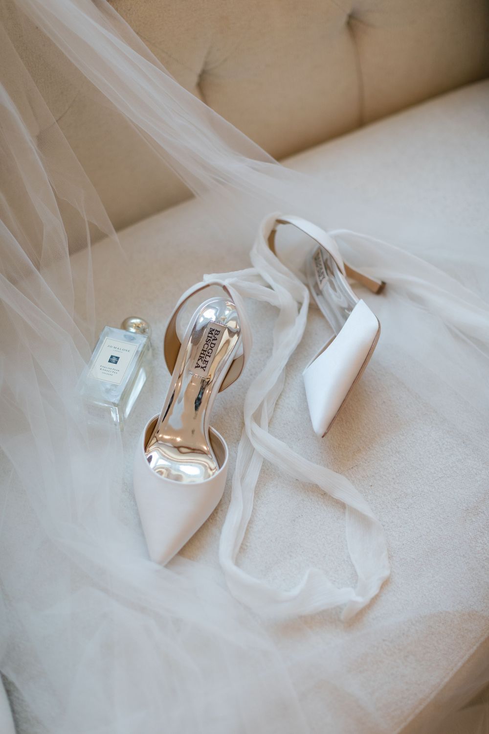 Elegant white bridal heels and perfume bottle displayed on soft tulle fabric. forbes farm saint simons getting ready
