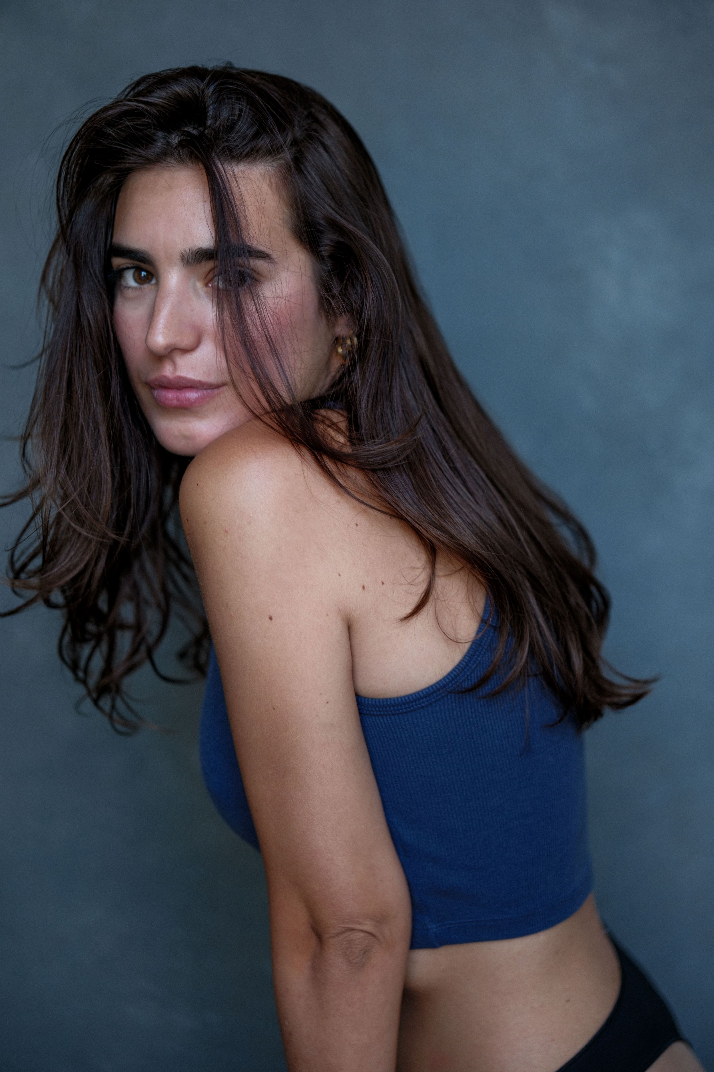 Athletic pose series in blue sports top against dark background with movement.