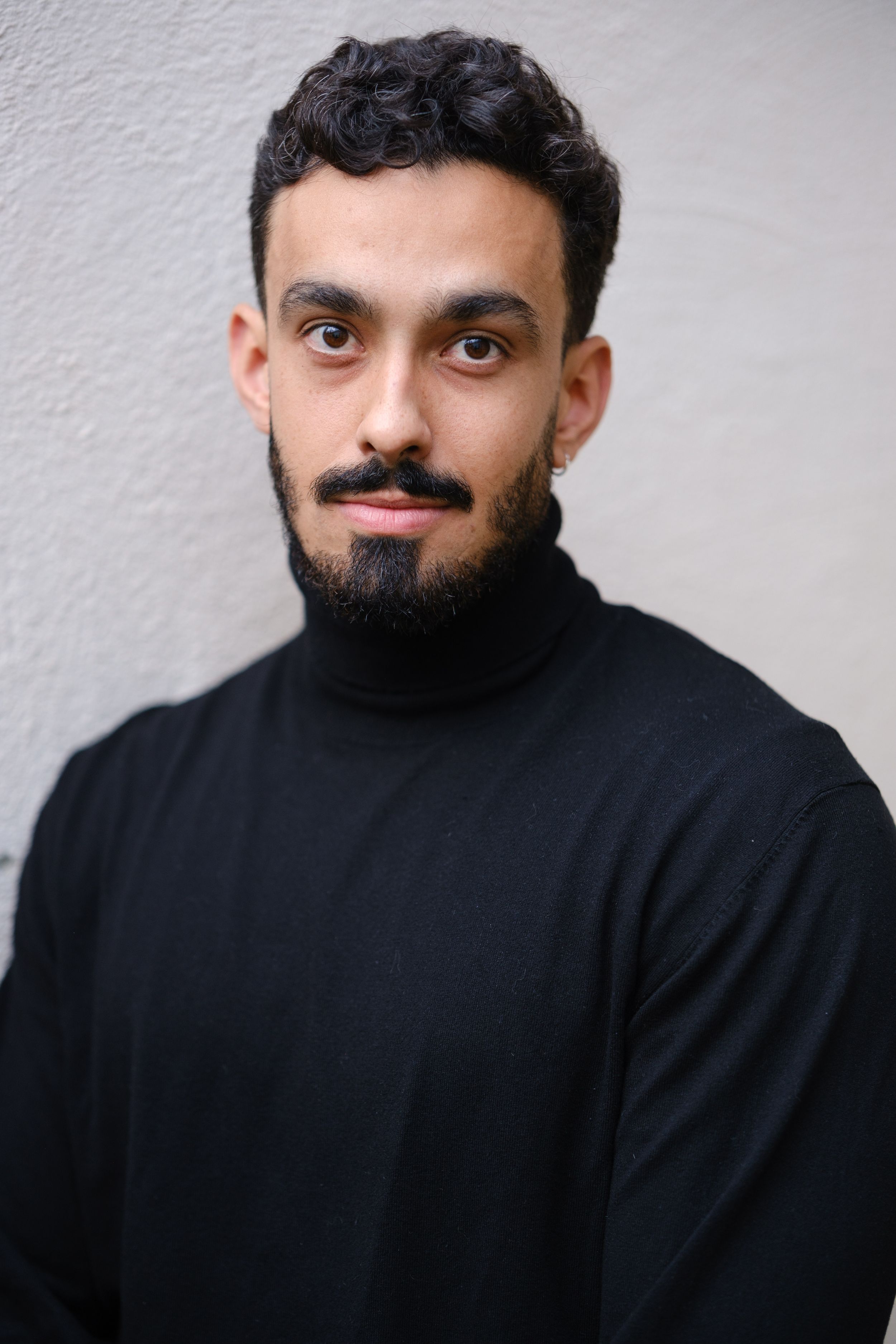 Modern portrait series of man in black turtleneck against light background.