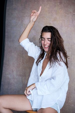 Dynamic poses in oversized white button-down shirt showing playful movement.