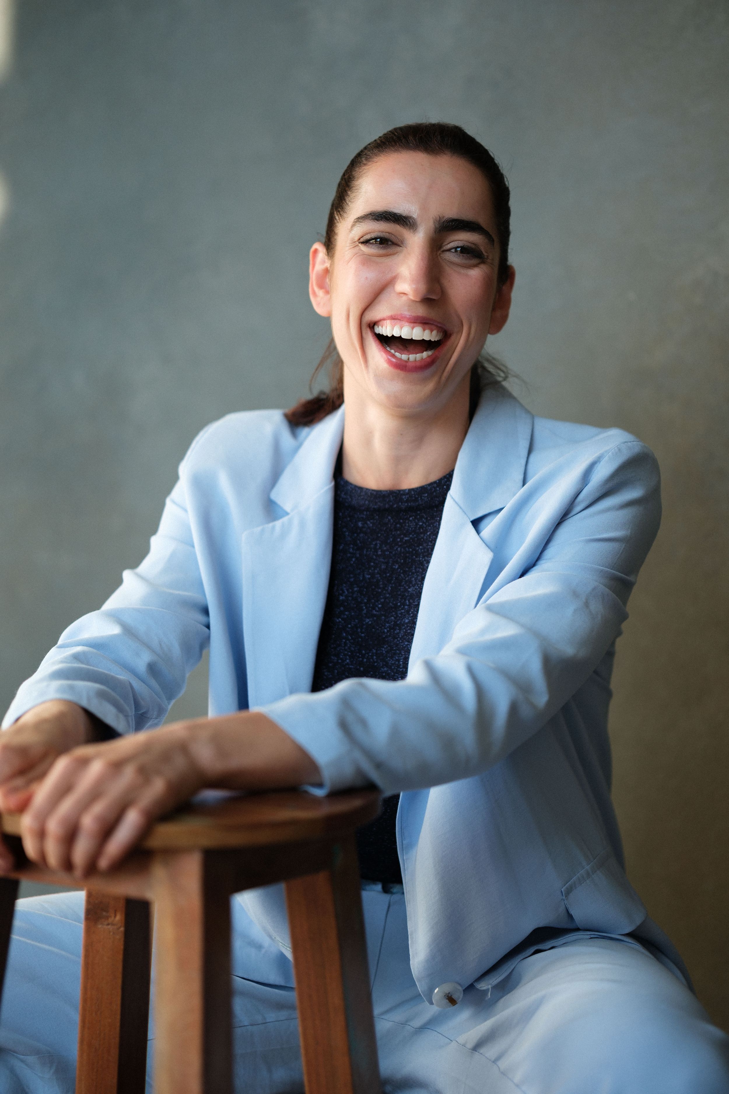 Portrait series showing joyful expressions while wearing a light blue blazer and dark top.