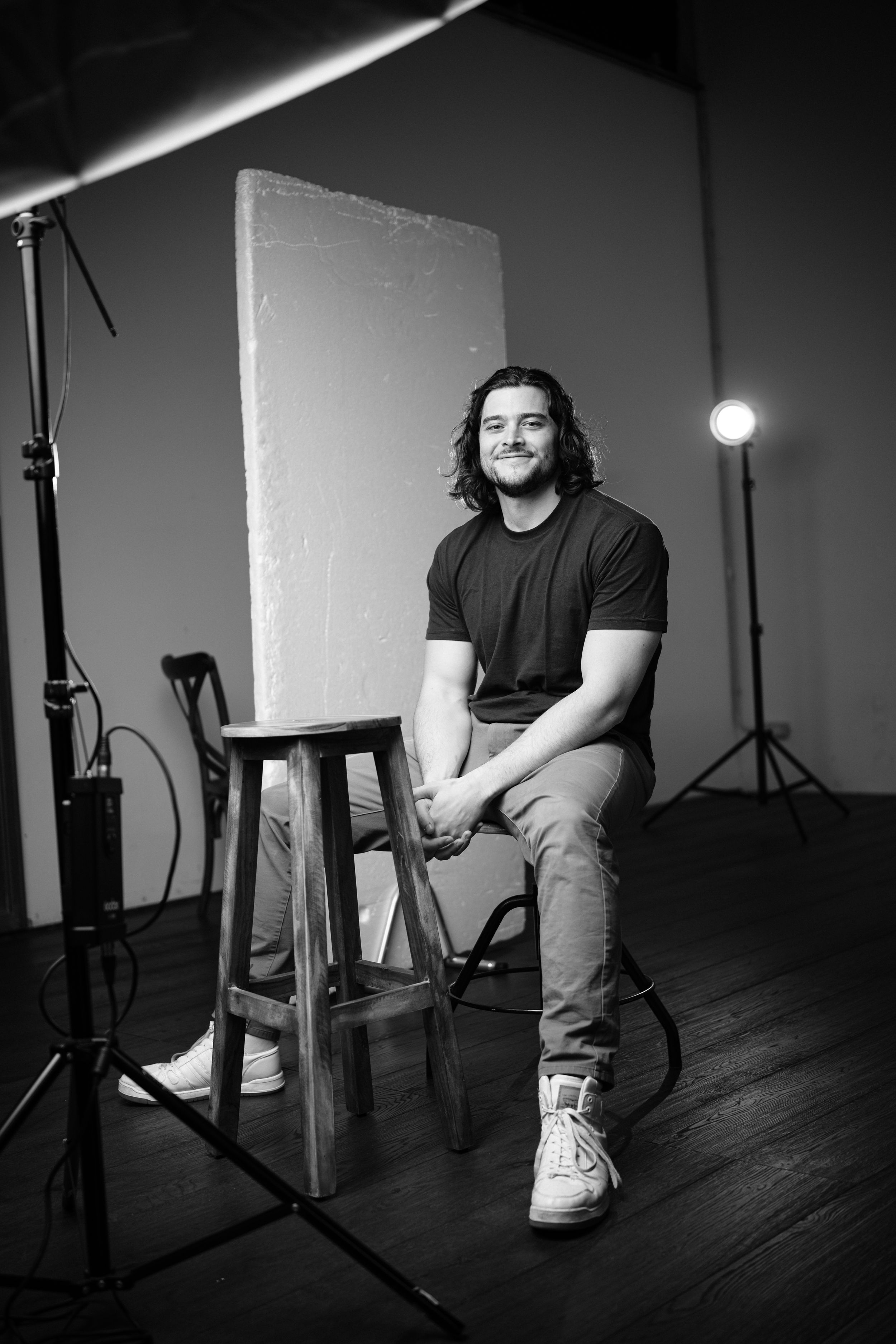 Black and white studio photo series showing someone seated on a stool with dramatic lighting.