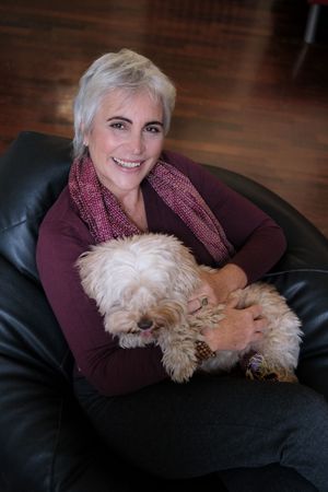 Heartwarming series showing person cuddling with fluffy white dog on leather couch.
