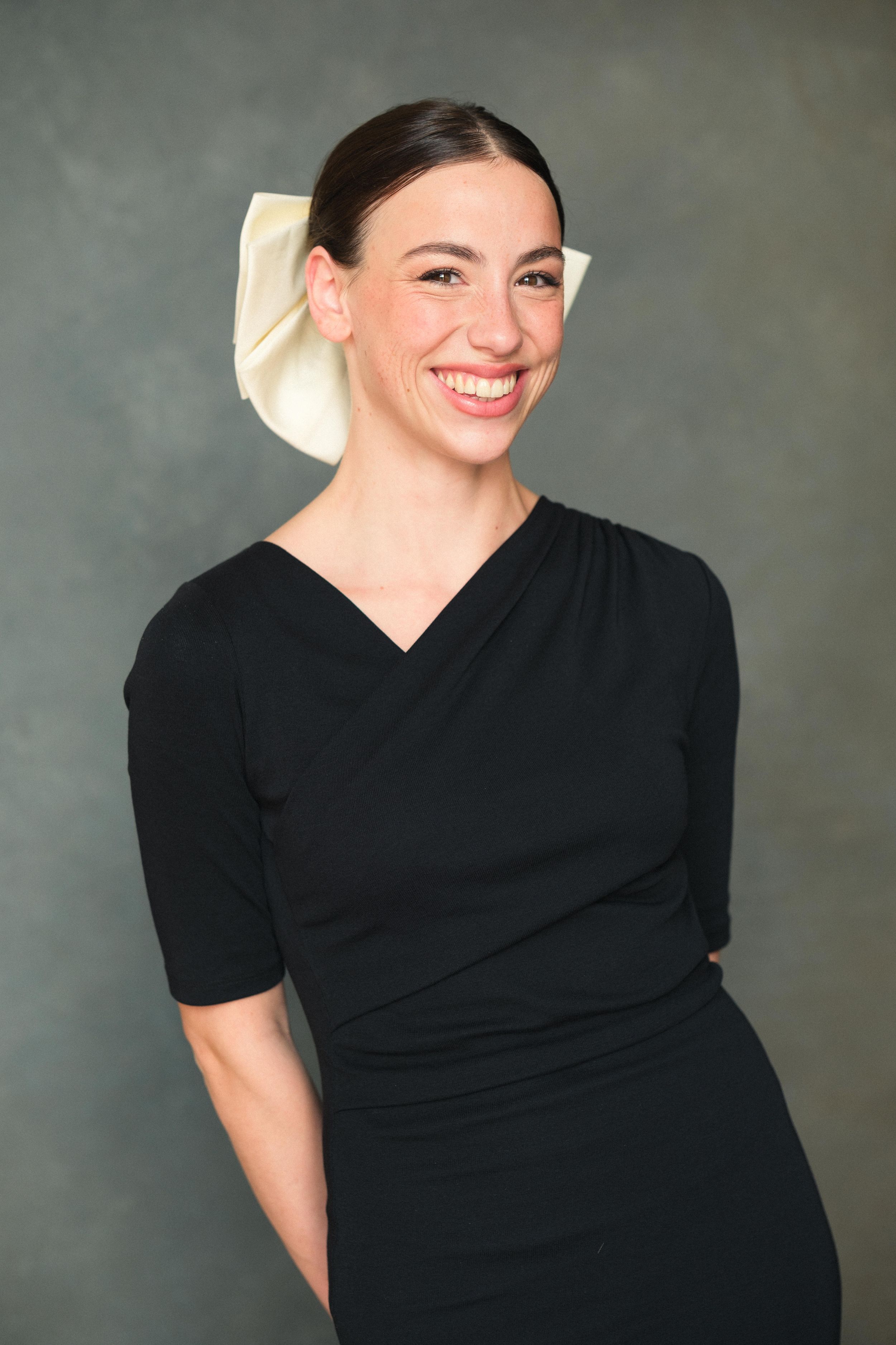 Portrait series in black dress with chef hat showing warm smiles and natural expressions.