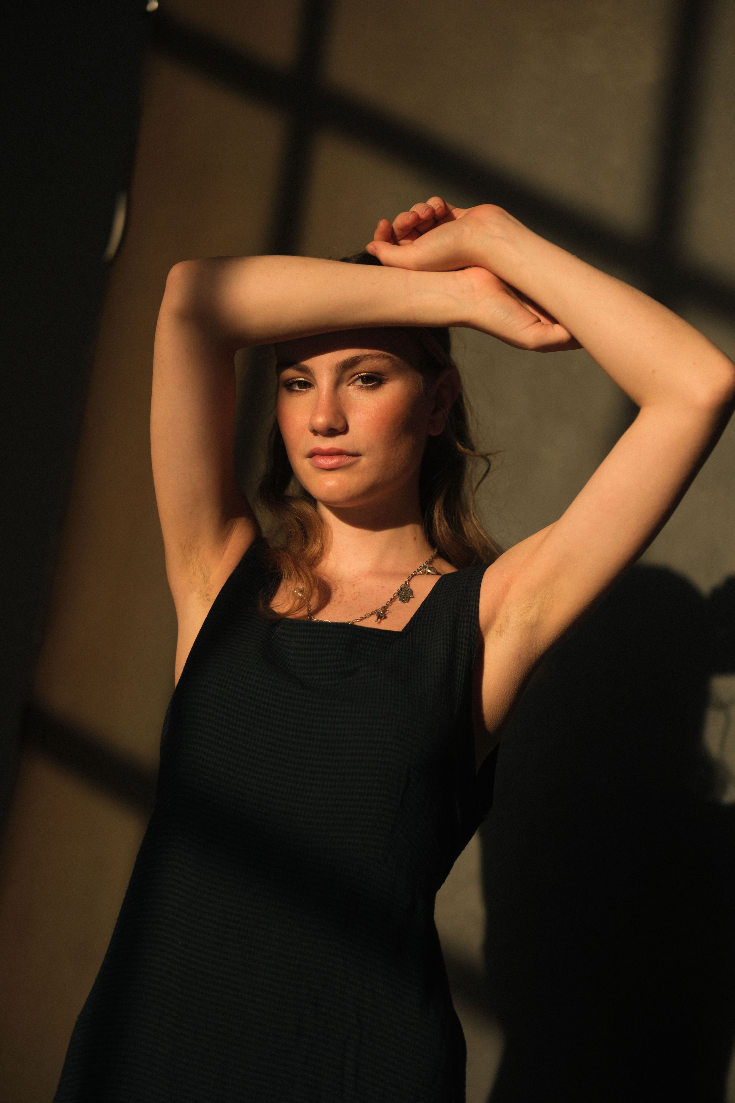 Artistic portrait series in black dress against dramatic lighting with shadows and highlights.