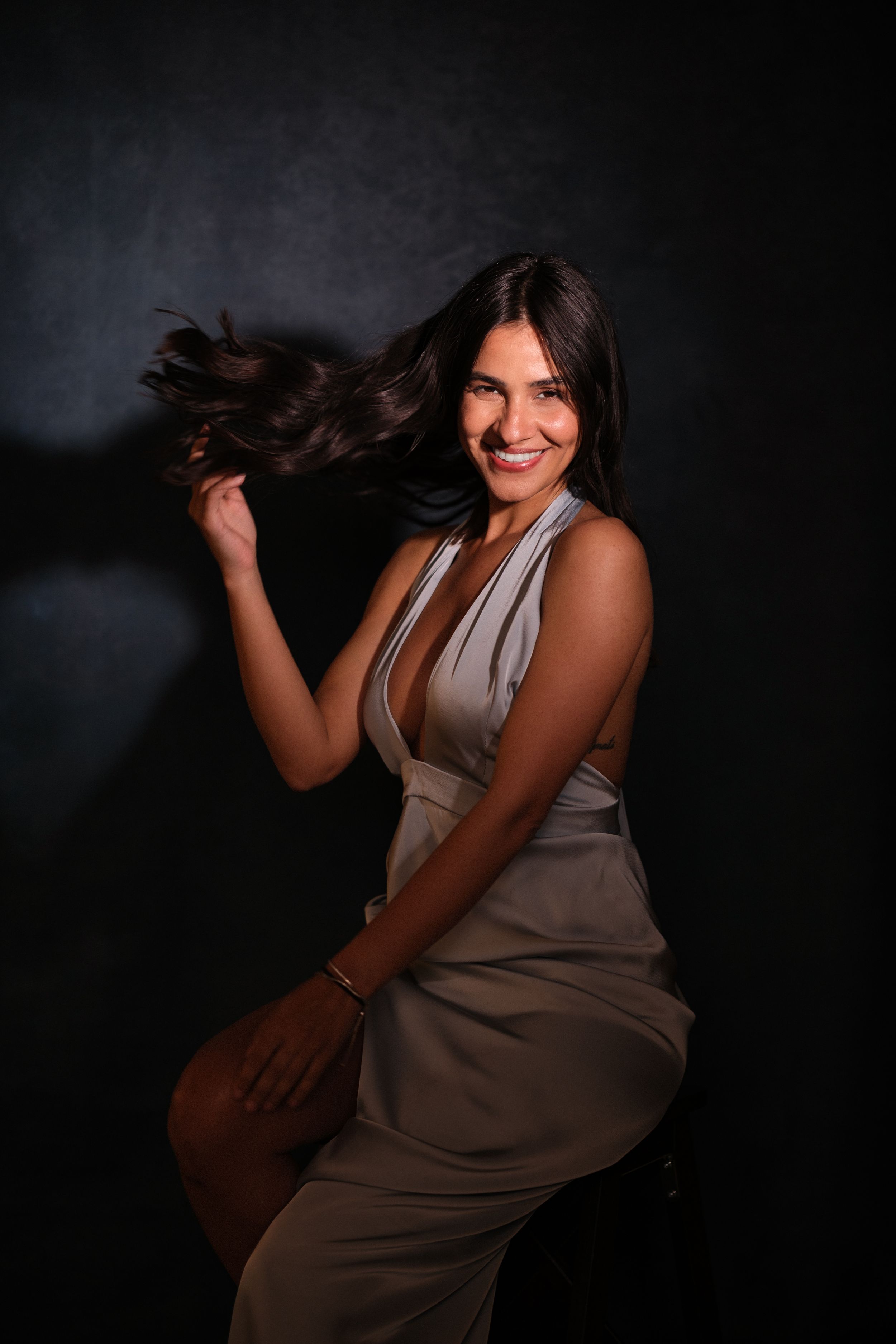 Energetic poses in beige dress against dark background showing movement and joy.