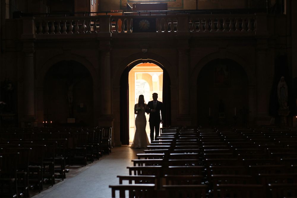 Silhouette of couple framed in church doorway with empty pews in foreground.
