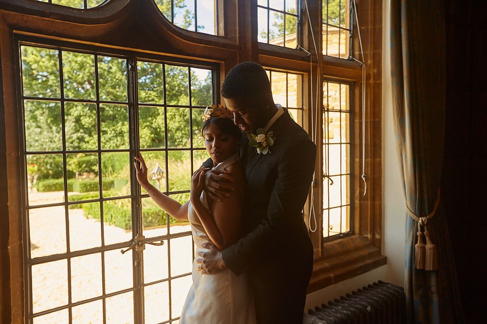Romantic silhouette of couple embracing by sunlit window in historic interior.