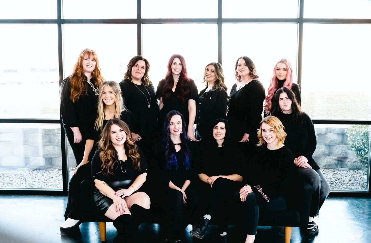 Group photo of people wearing black formal attire in modern building with windows.