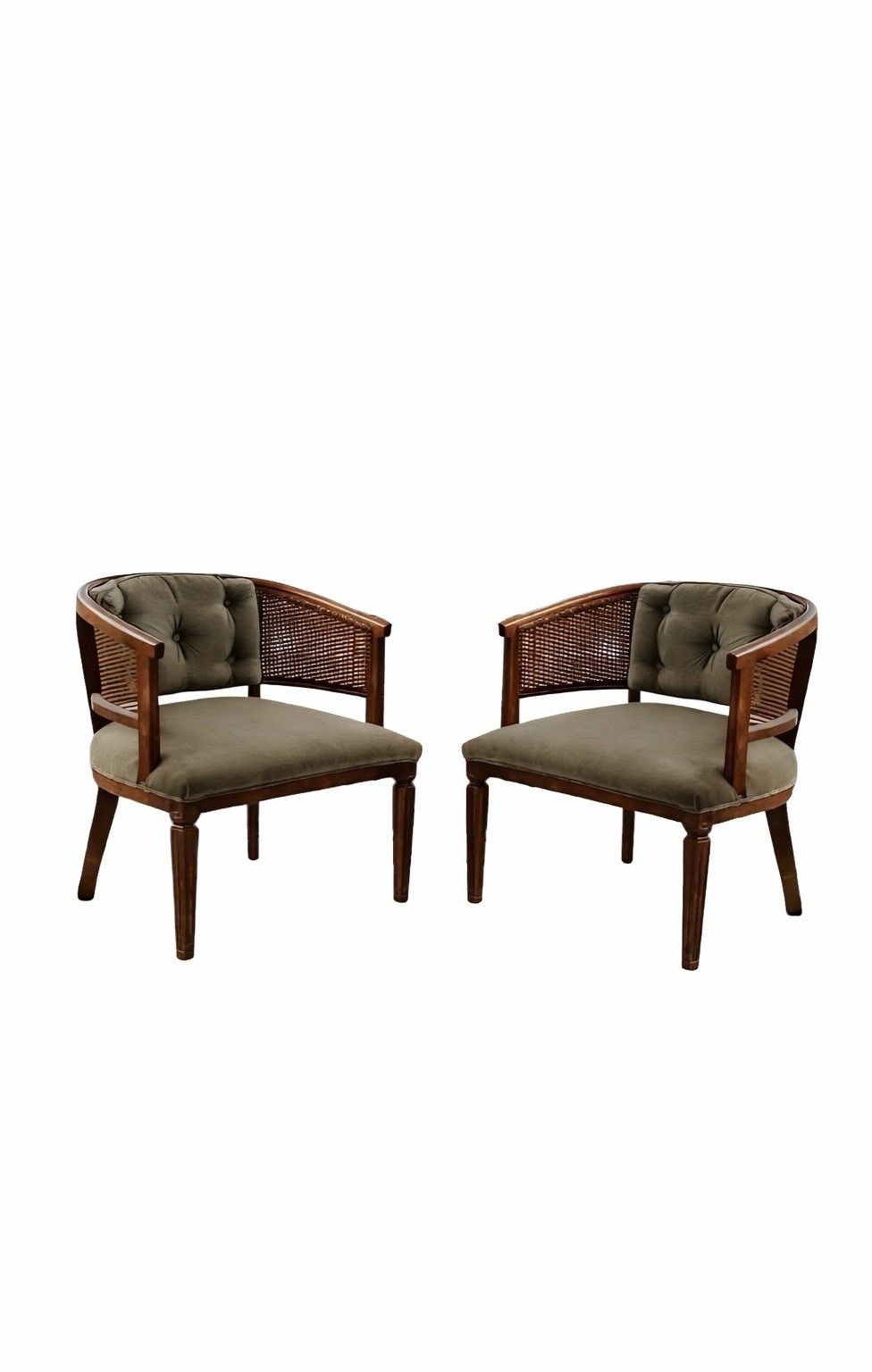 Two vintage red leather armchairs with oval backs sit on grass in a garden setting with trees in the background.