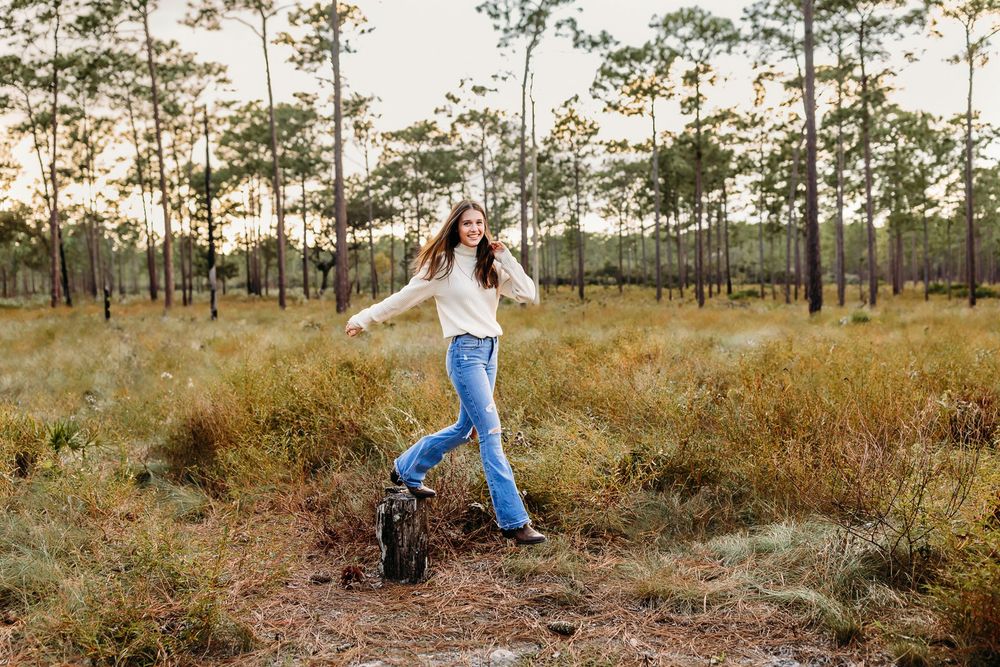 A rural outdoor portrait photo session at golden hour with pine trees and tall grass in late autumn setting.