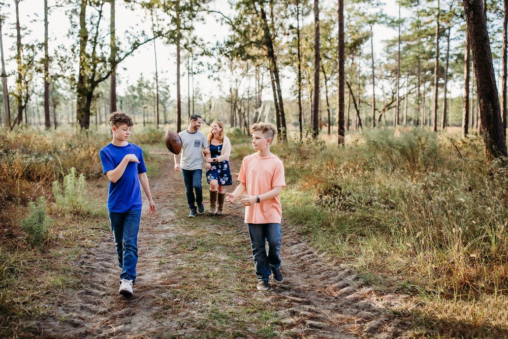 A group taking a peaceful walk together on a forest trail surrounded by tall pine trees on a sunny day.