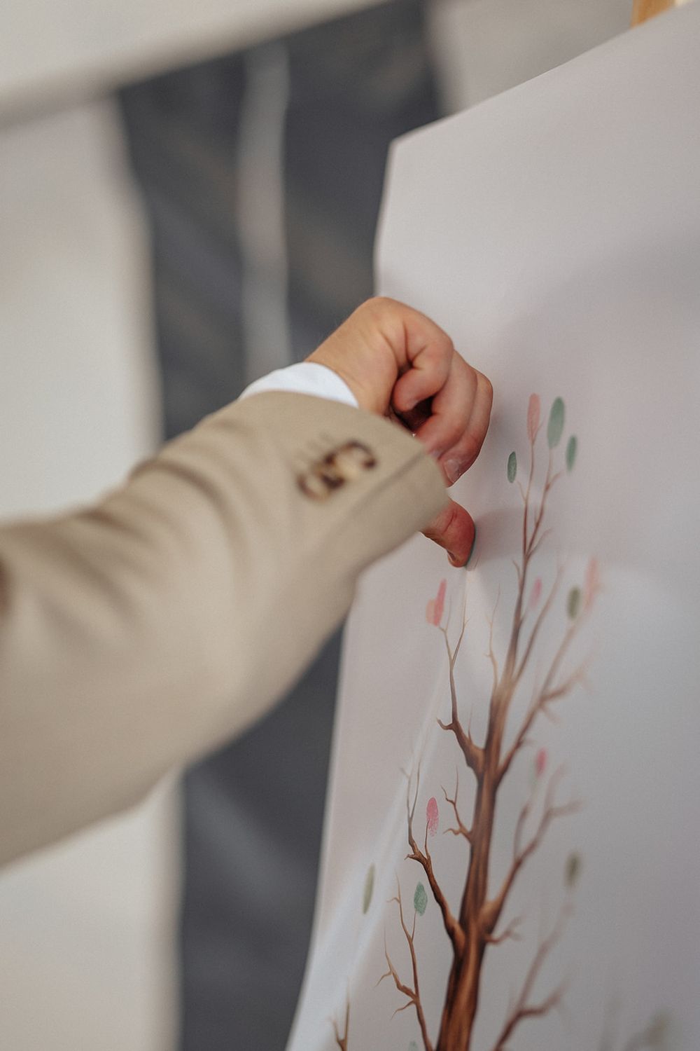 Close-up view of hands arranging paper art pieces showing delicate tree branches with pink blossoms.