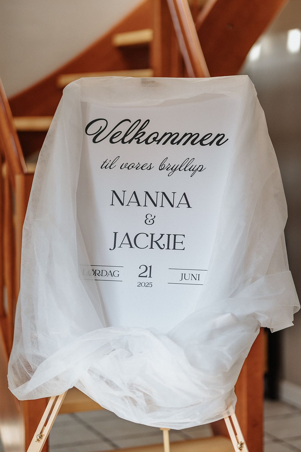 White fabric name cards with elegant script text displayed on wooden stands create an elegant wedding seating arrangement.