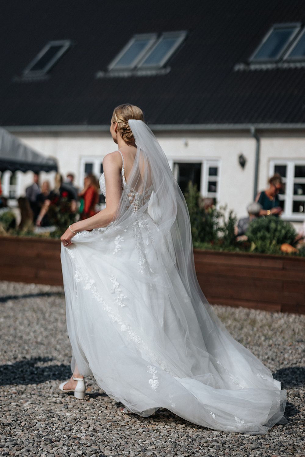 A flowing white wedding dress train trails elegantly across gravel ground in a series of romantic detail shots.