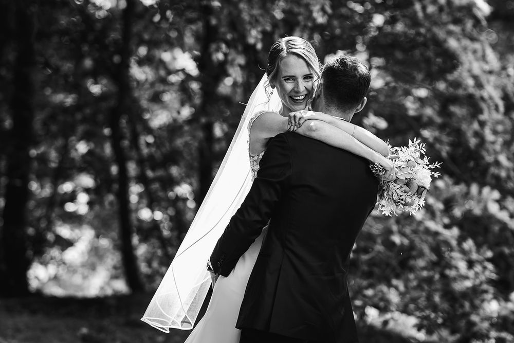 A black and white wedding photo series shows romantic moments between a couple in an outdoor garden setting.