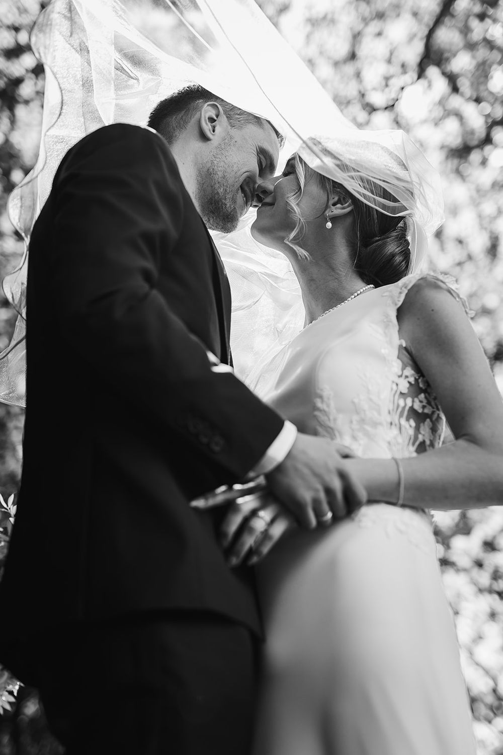 A romantic black and white wedding photo series showing intimate moments between the bride and groom during their first kiss.