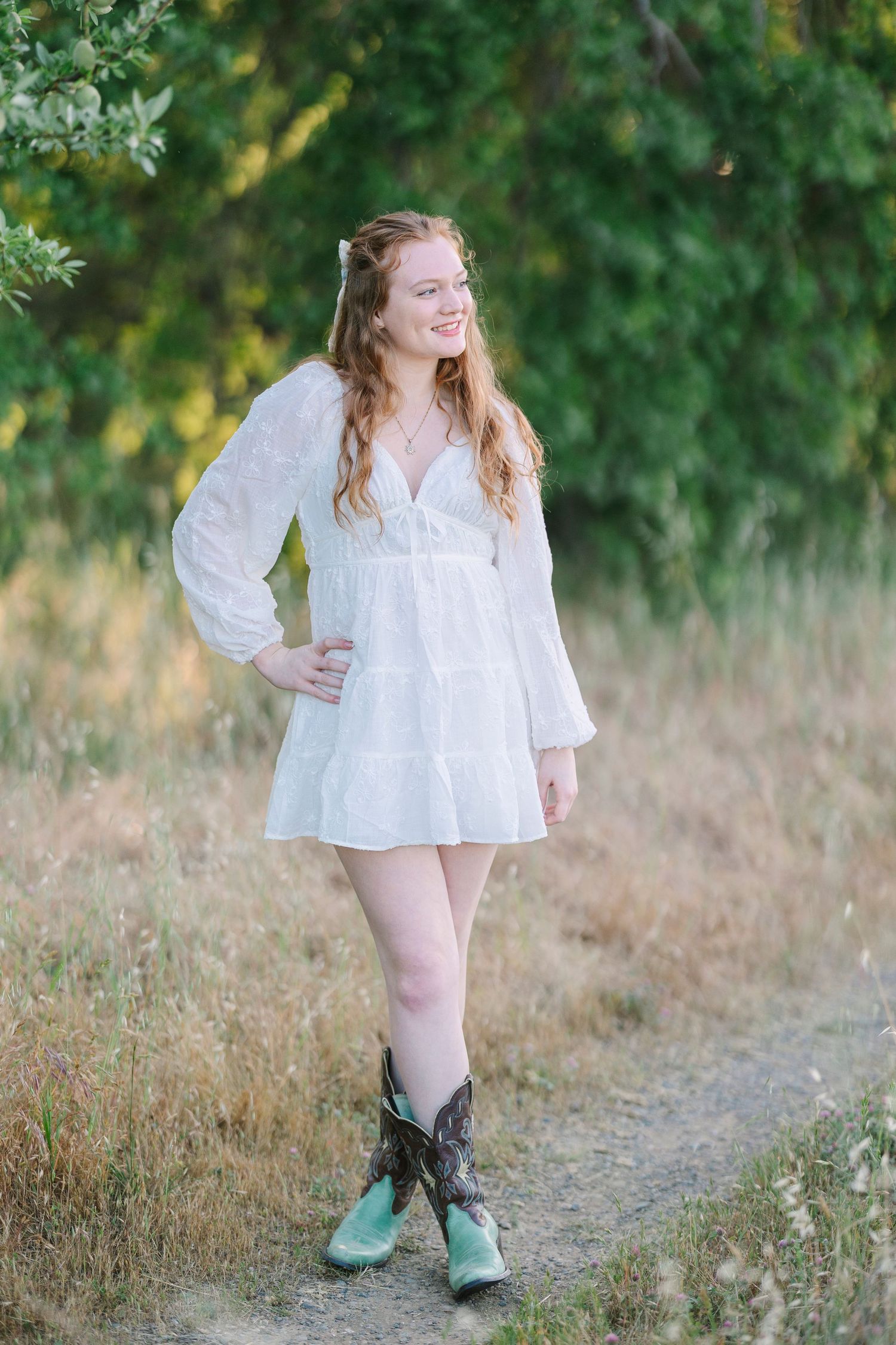 Whimsical outdoor photoshoot with green boots and flowing white dress in a field.