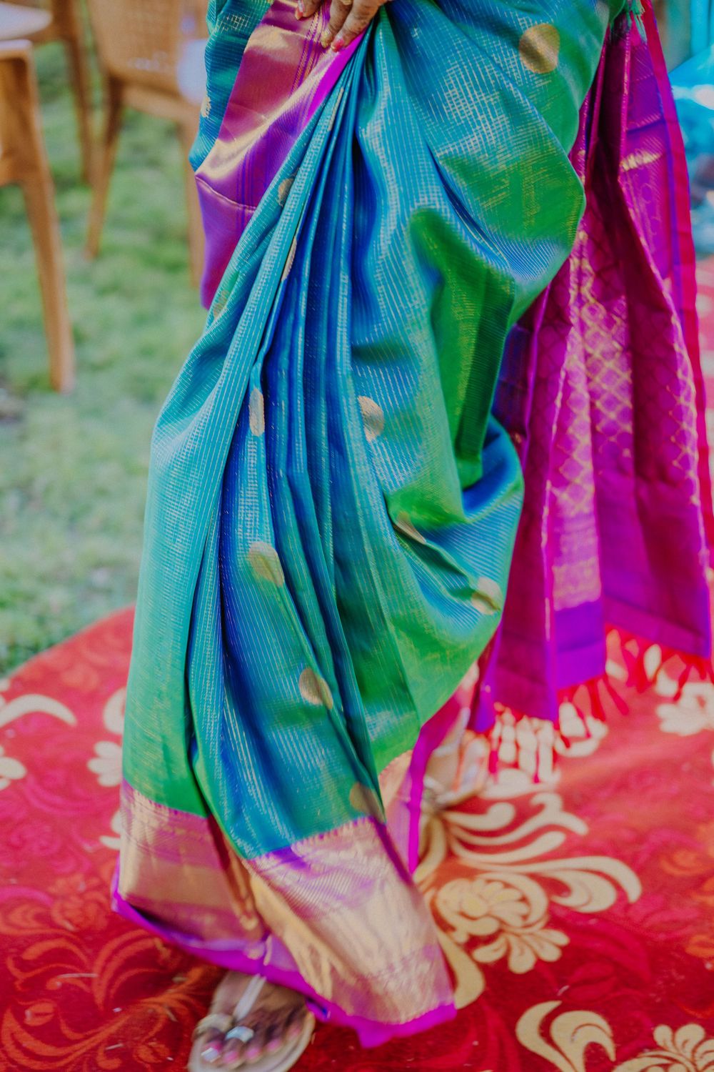 Close-up view of vibrant blue and magenta silk saree with traditional patterns on a red carpet.