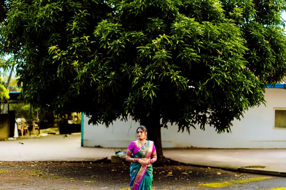 A person walks along a tree-lined path next to a white building on a sunny day.