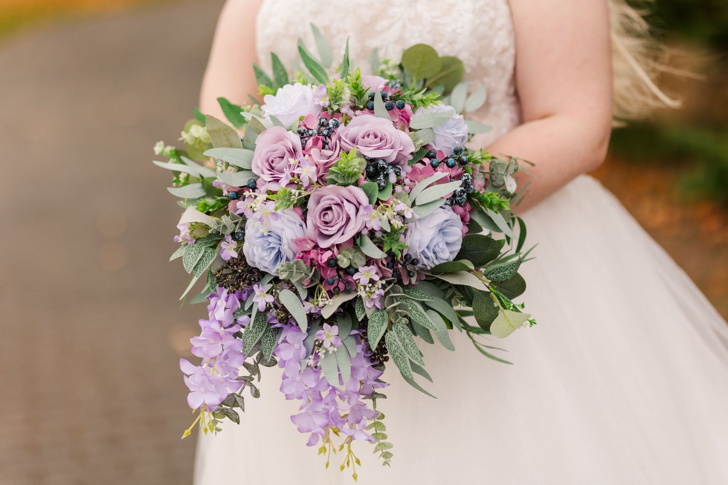 A romantic bridal bouquet featuring lavender and purple roses with cascading greenery and delicate foliage.
