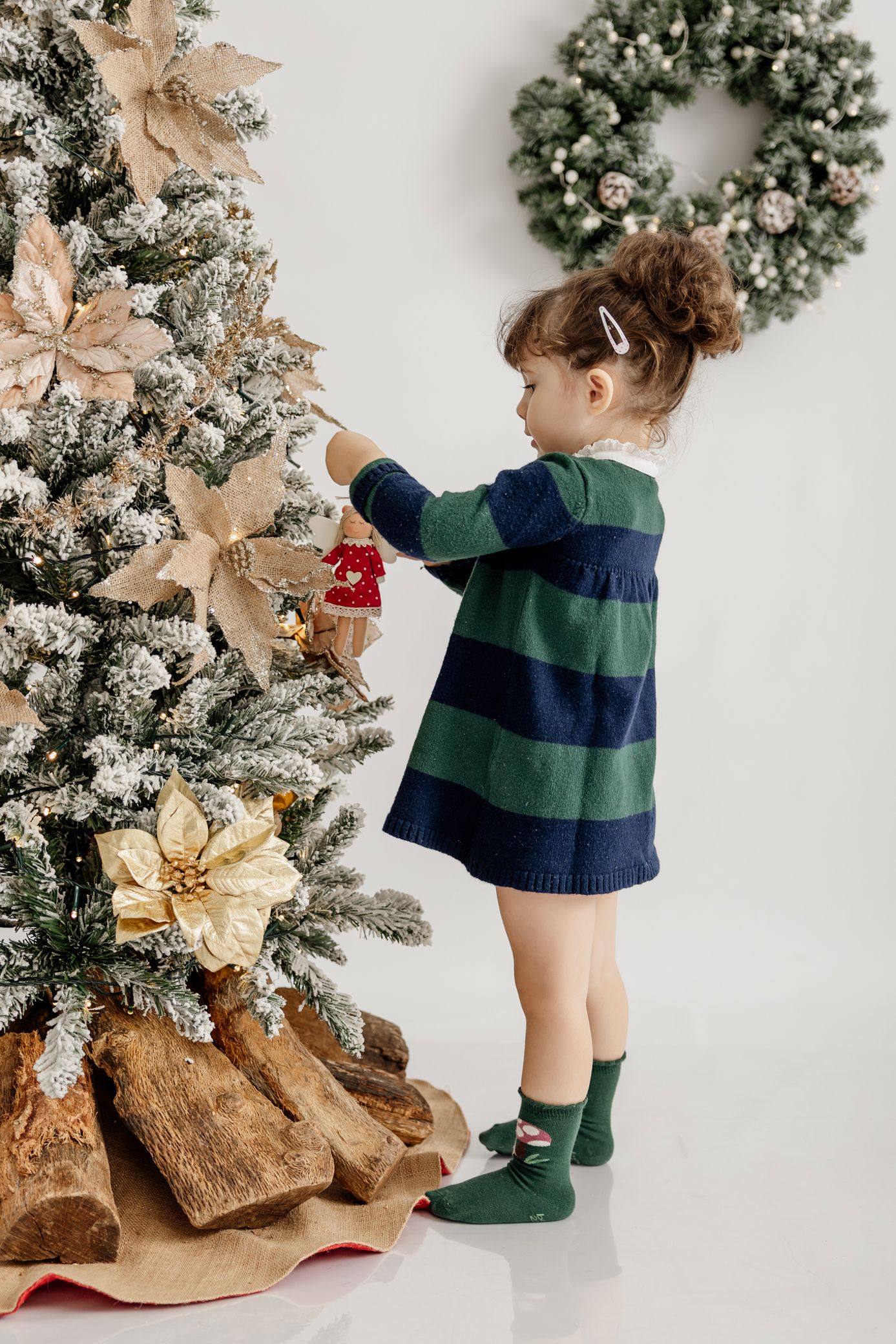 A young person in a striped sweater lies on a wooden bench near a decorated Christmas tree and holiday decor.