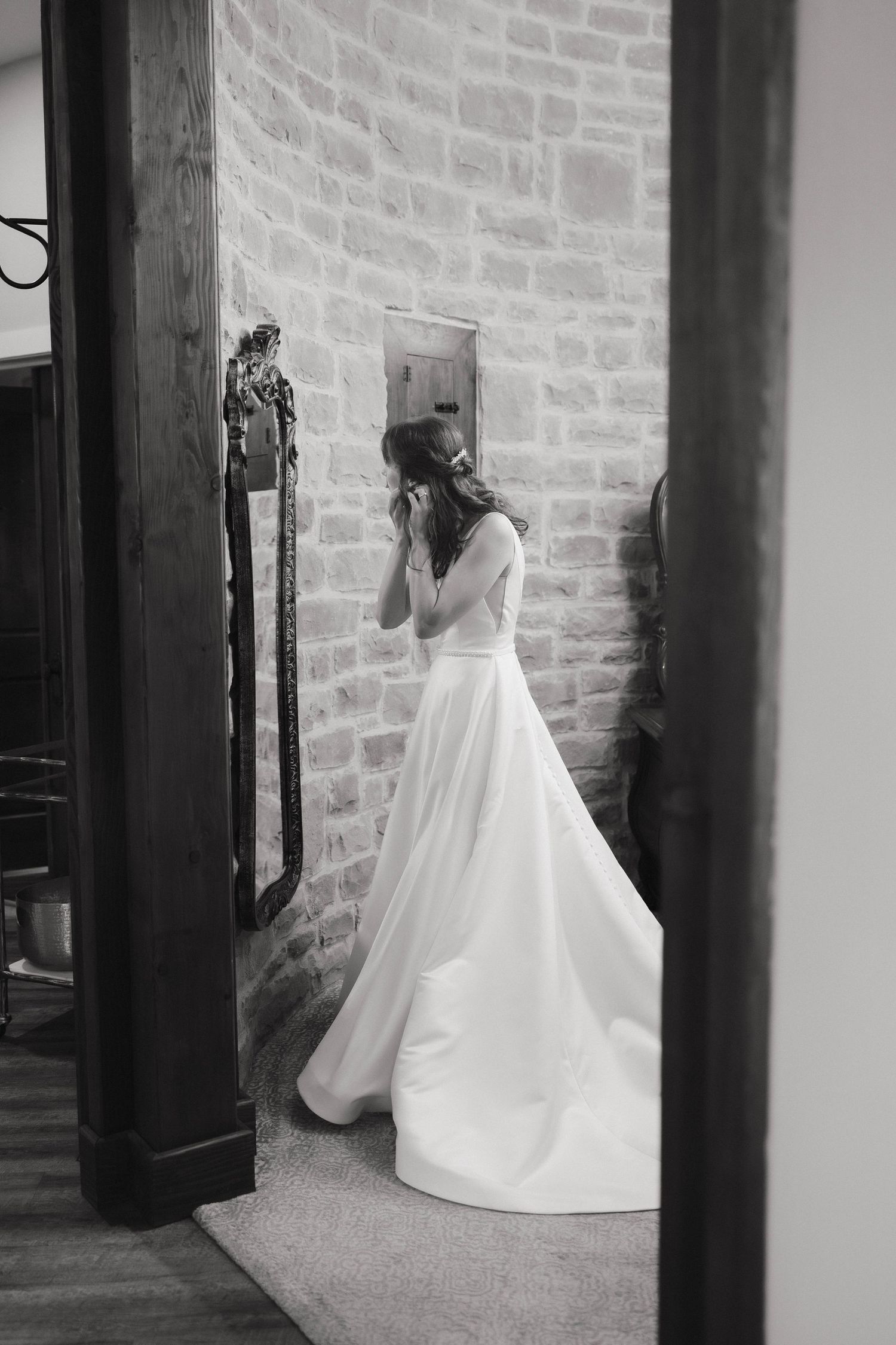 Black and white photo of a wedding dress silhouette against stone walls and wooden beams.