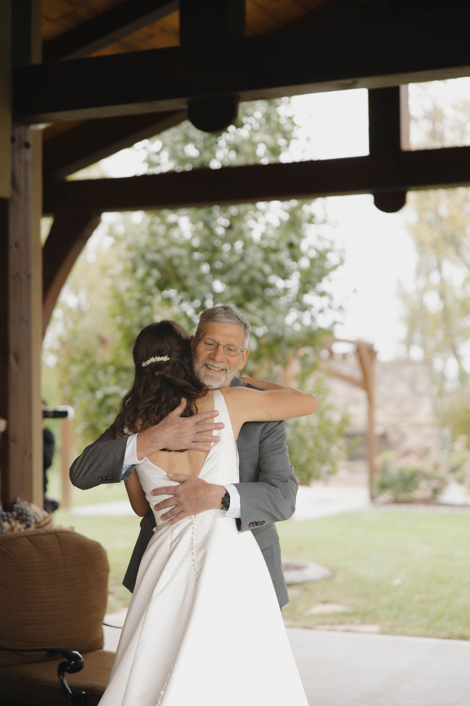 A touching first look moment between two people embracing under a covered outdoor area.