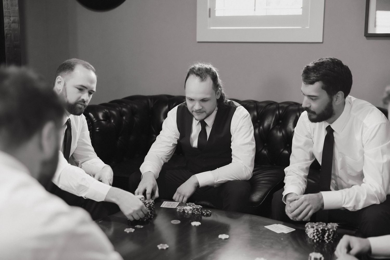 Men playing cards at a table during what appears to be a wedding celebration or formal event.