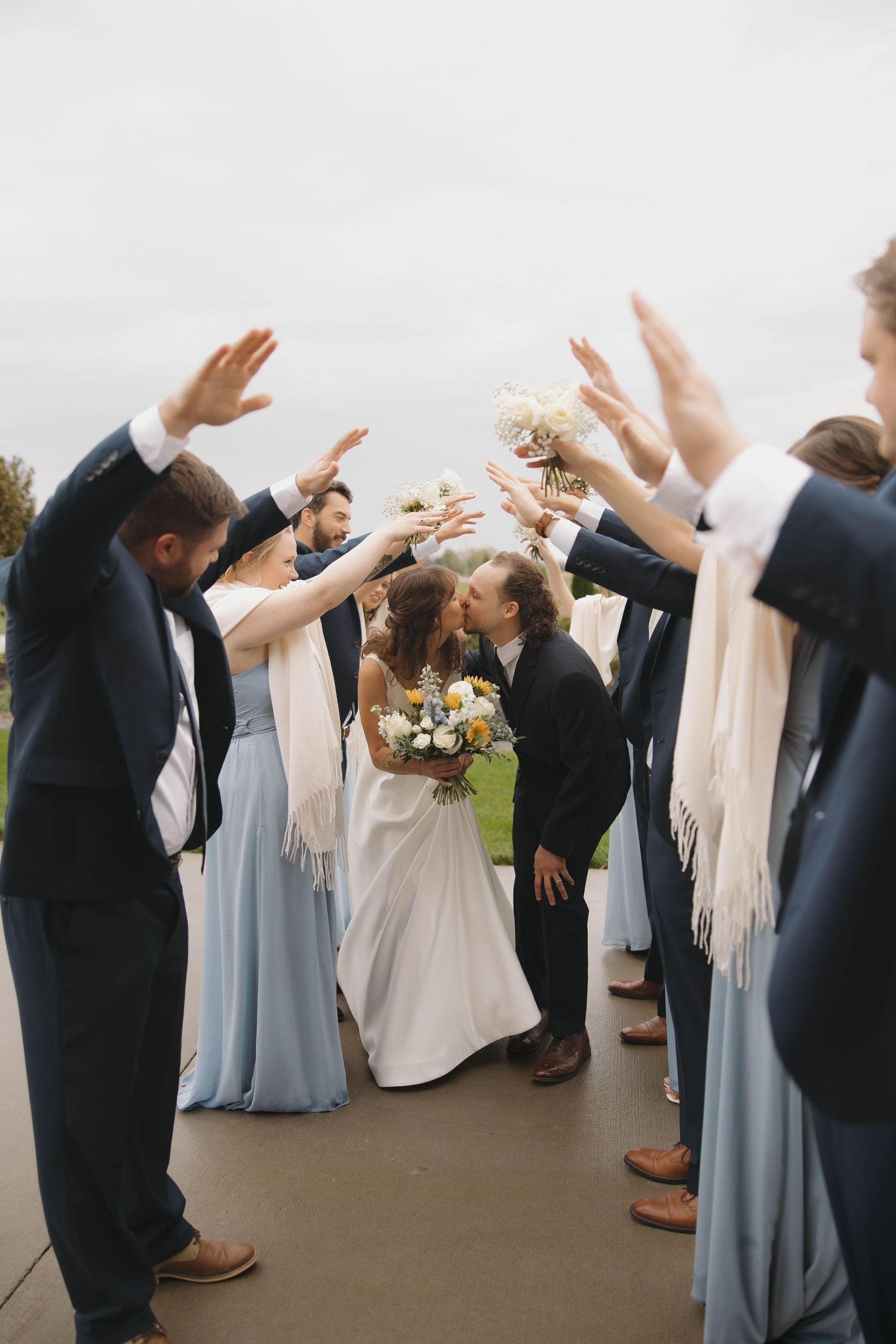 Wedding party members dancing with arms raised in celebration wearing formal attire.