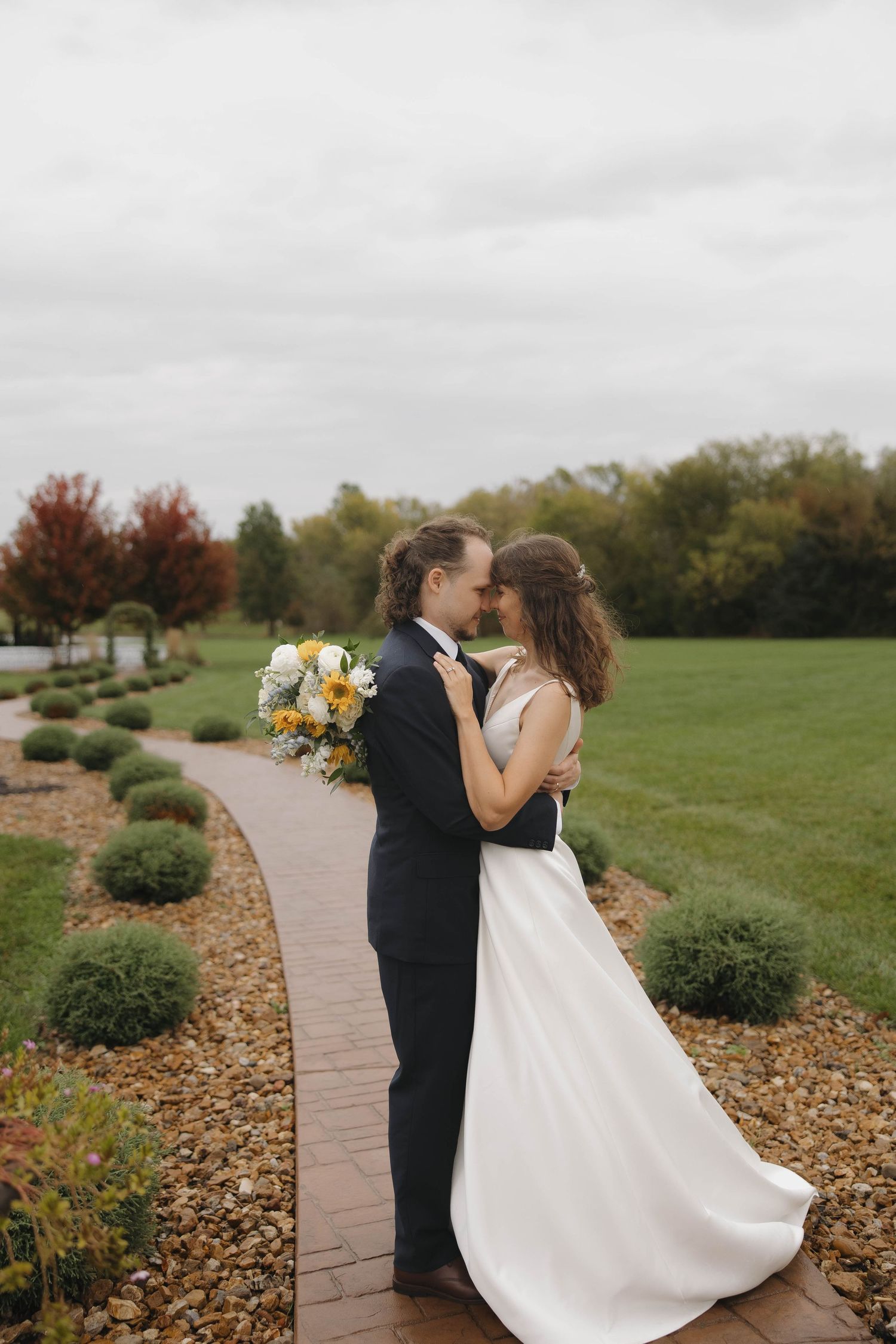 A romantic dance pose on a stone pathway surrounded by autumn landscaping.