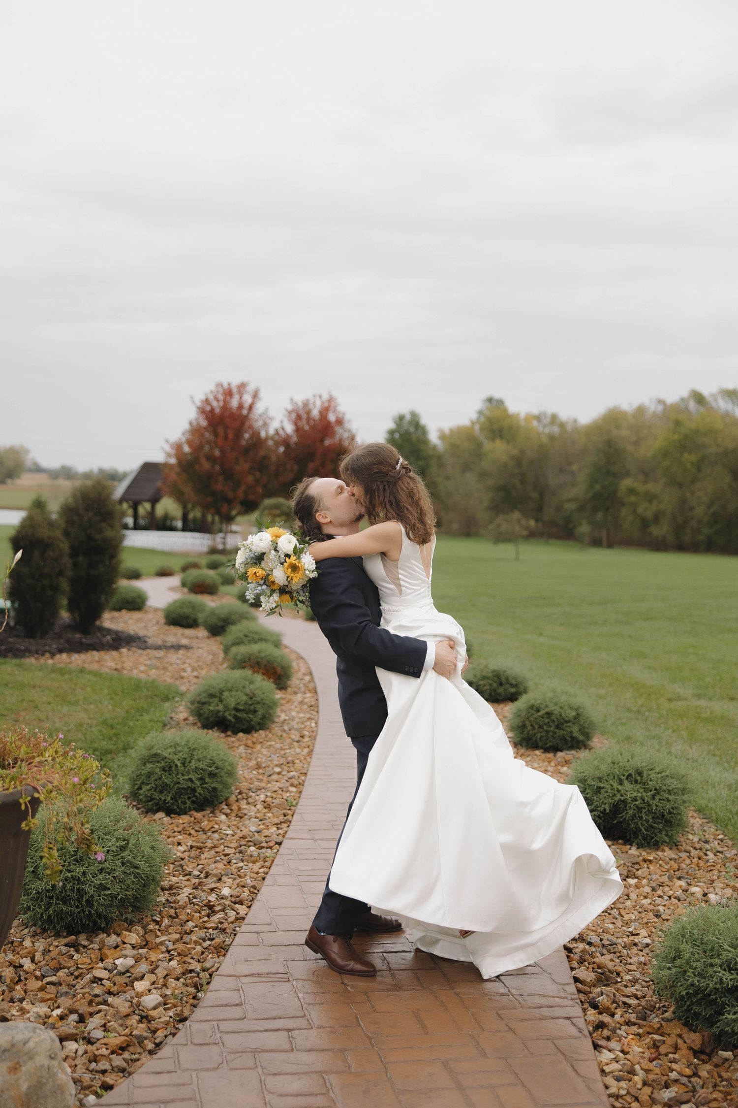 A dramatic dip dance move performed on a stone pathway with fall foliage in the background.