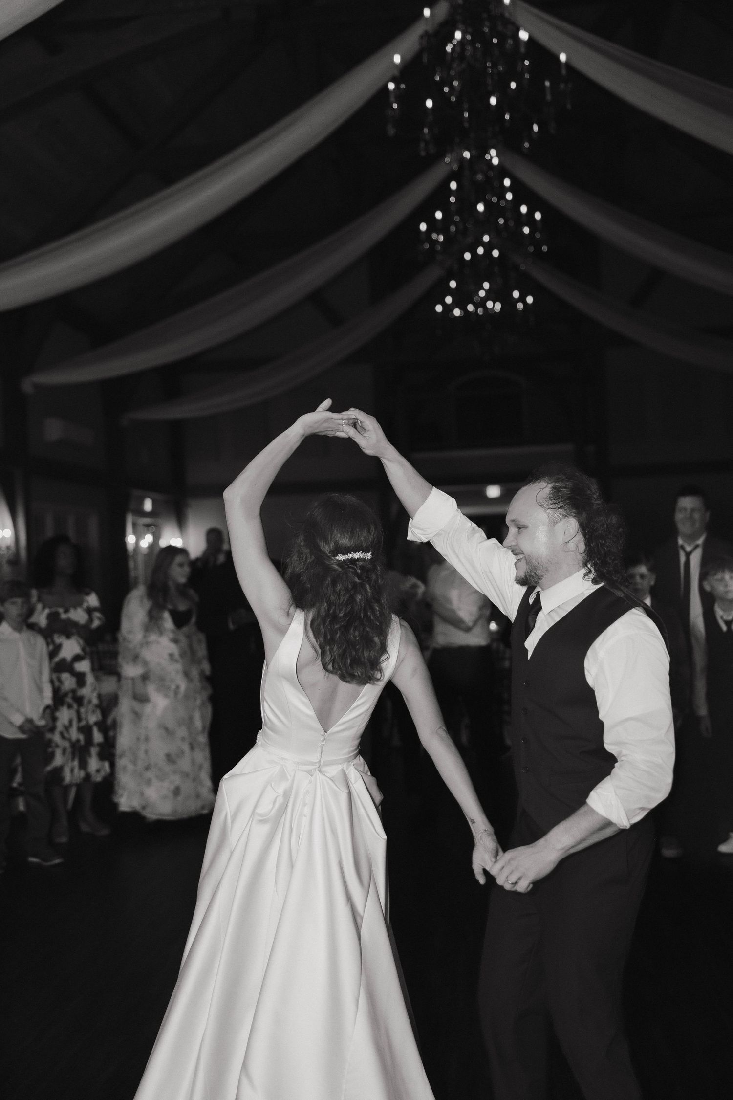 A couple dances under twinkling lights at their wedding reception in a dark tent venue.