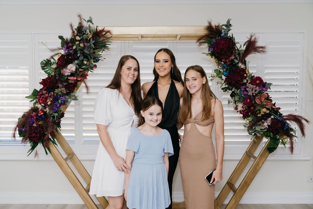 Decorative wooden arch with purple and burgundy floral arrangements against white wall.