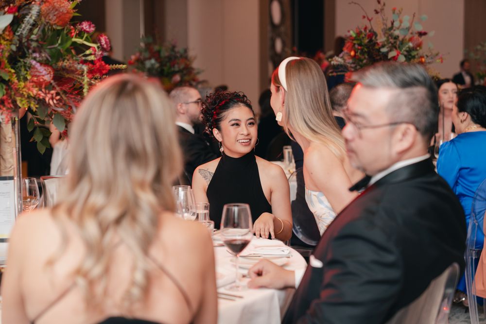 Guests enjoying conversation during an elegant dinner party with red floral decorations.