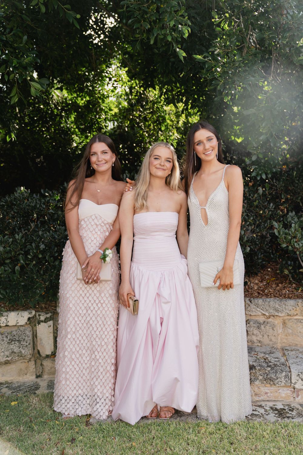 Group wearing coordinated pink and cream dresses posing together in a garden setting.
