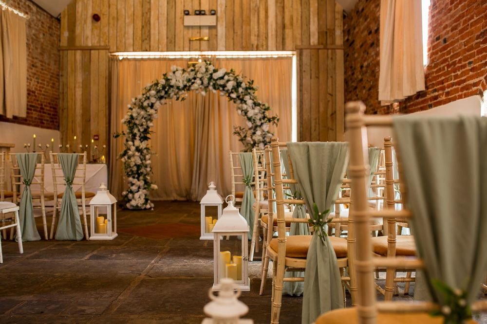 Rustic wedding reception space with lanterns and sage green accents.