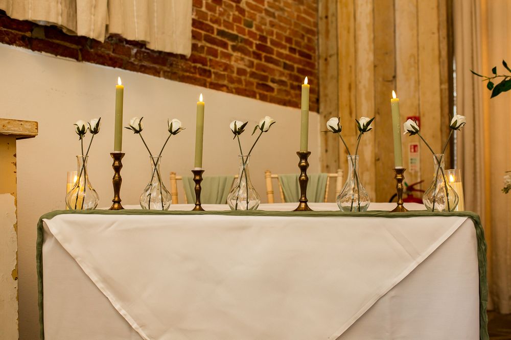 Elegant wedding venue interior with exposed brick walls, wooden beams, and white floral decorations.