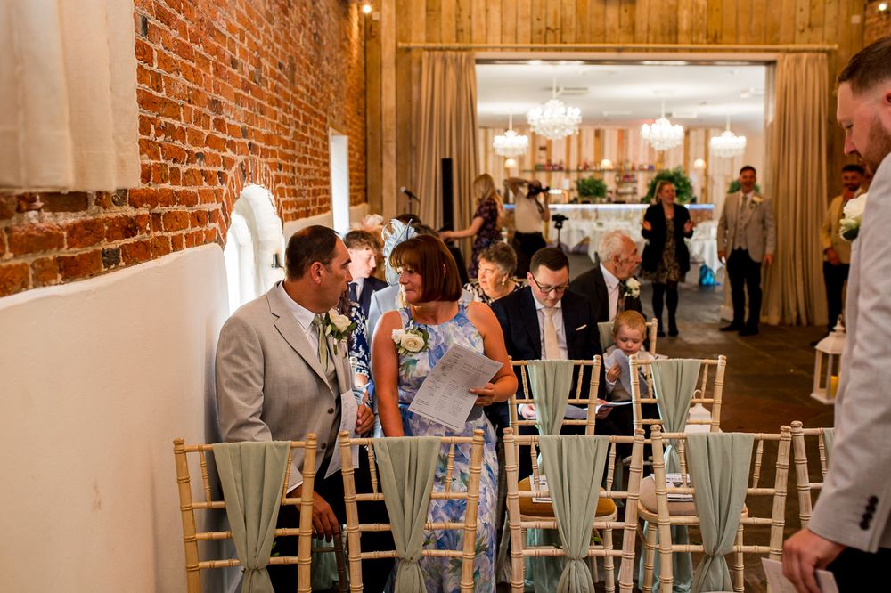 Wedding reception venue with exposed brick walls and light gray chairs.