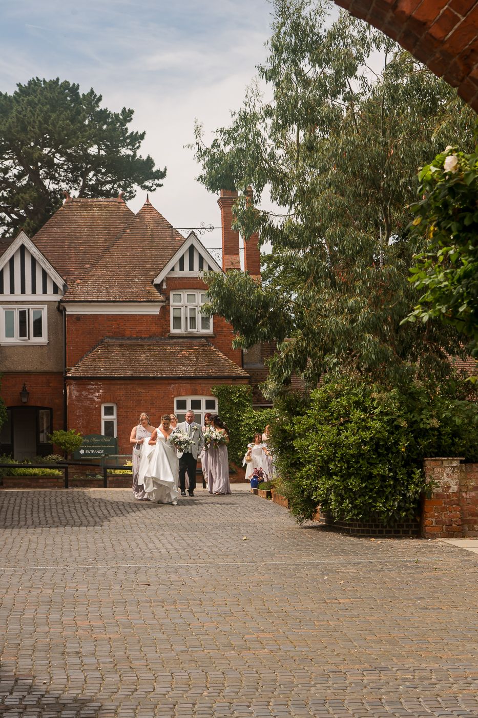 Traditional brick manor house with Tudor-style architecture and cobblestone driveway.