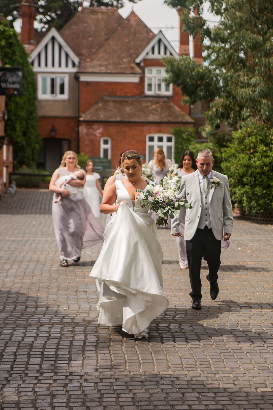 Wedding celebration on cobblestone courtyard with white and gray attire.