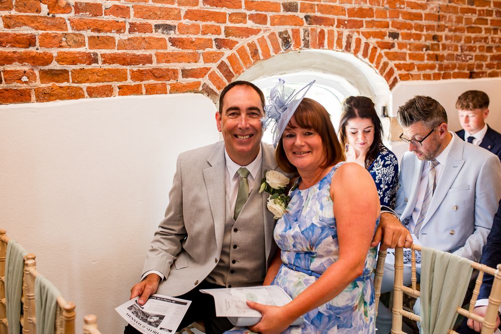 Wedding guests seated in a rustic brick-walled venue during a ceremony.