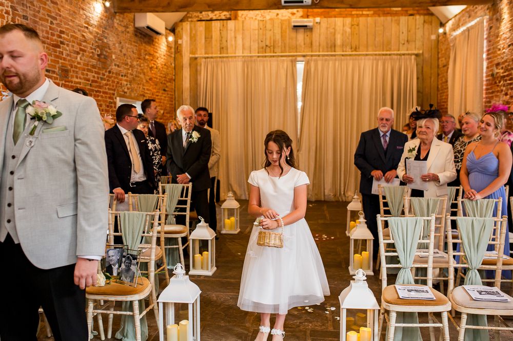 Wedding ceremony in a rustic barn venue with white lanterns lining the aisle.