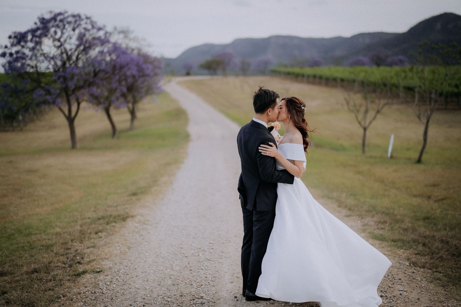 A romantic wedding photoshoot in front of a white building at sunset.