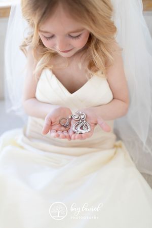 A bride in a white gown delicately holds silver owl charms in her hands.