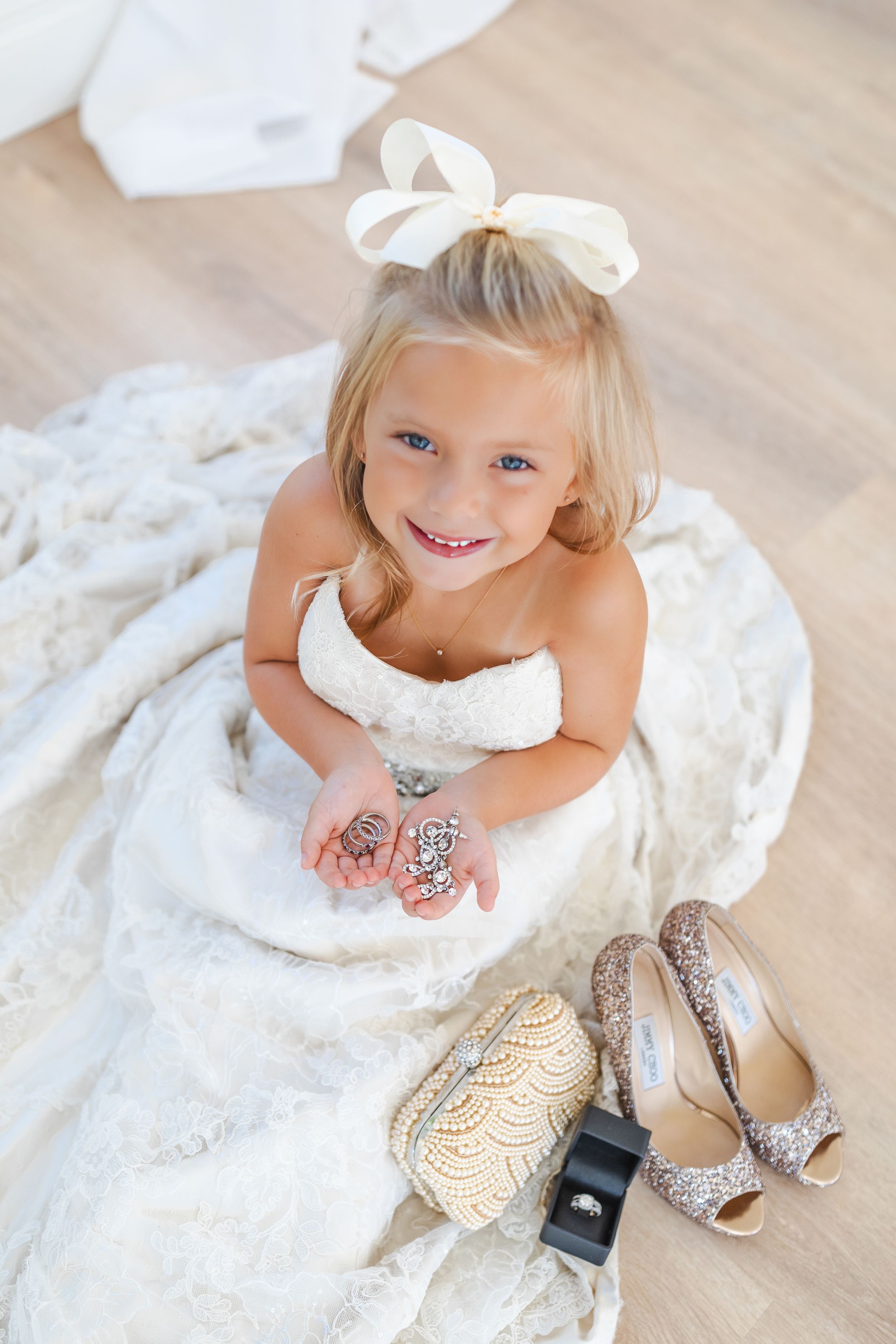 Wedding detail shot featuring elegant shoes and jewelry on light wooden flooring.