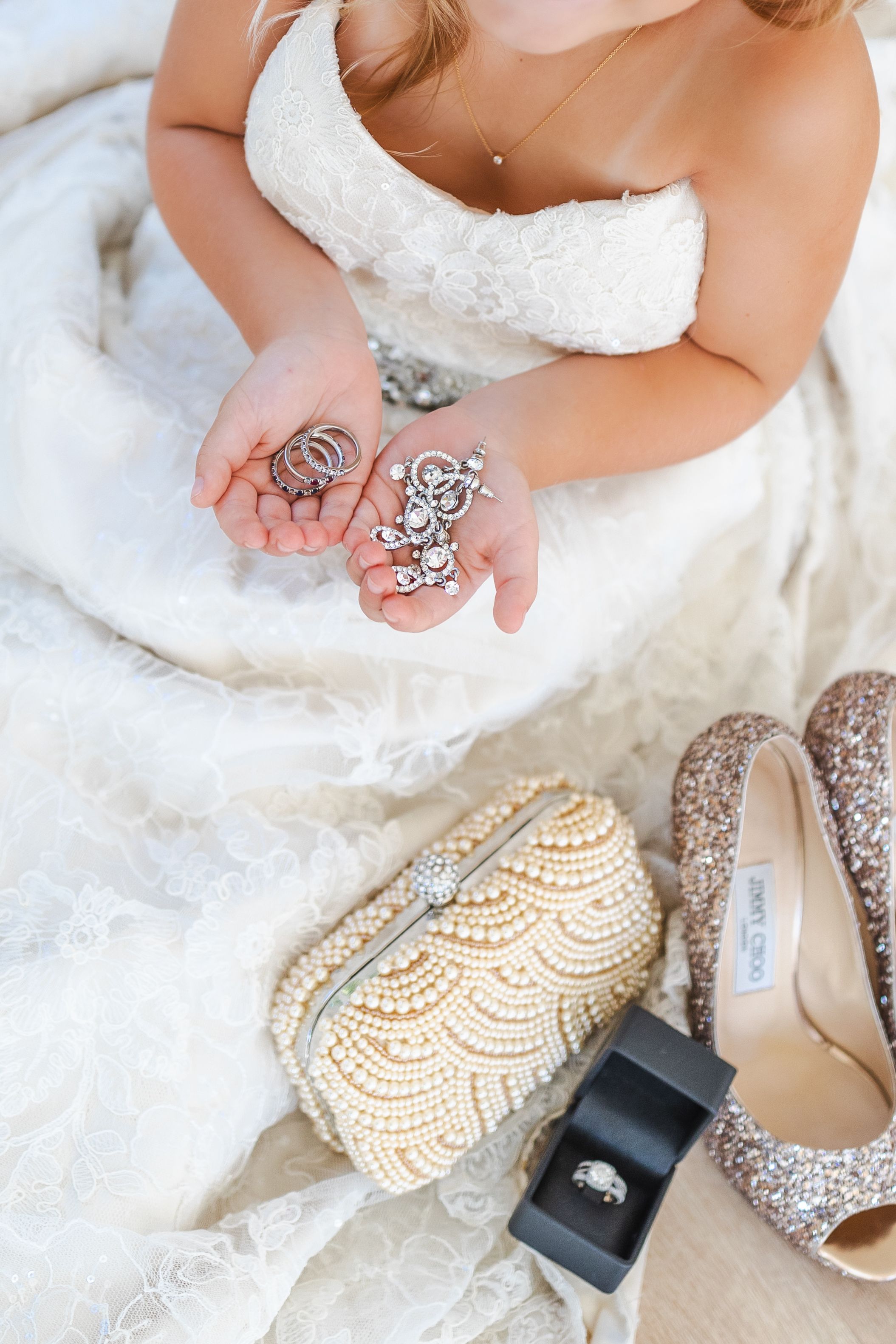 Wedding accessories including sparkly shoes and jewelry arranged on white lace fabric.